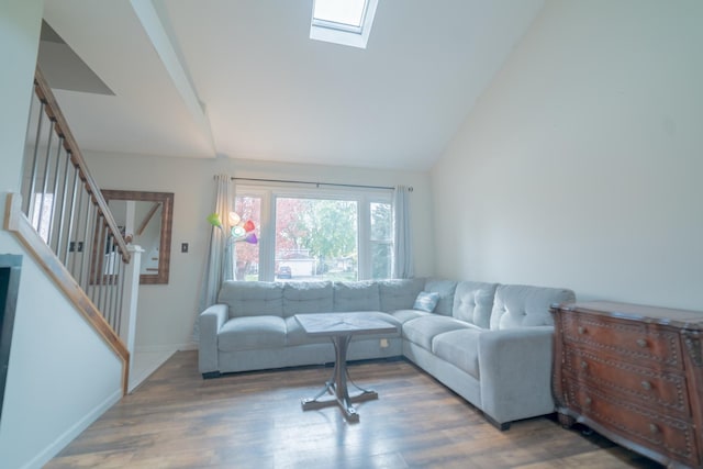 living room featuring wood-type flooring and vaulted ceiling with skylight