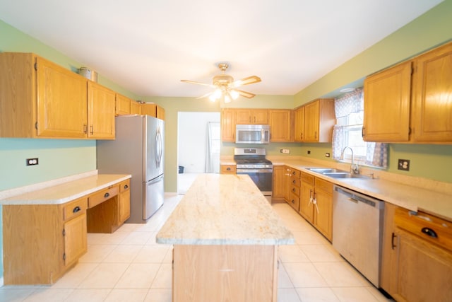 kitchen featuring sink, light tile patterned floors, appliances with stainless steel finishes, a kitchen island, and ceiling fan