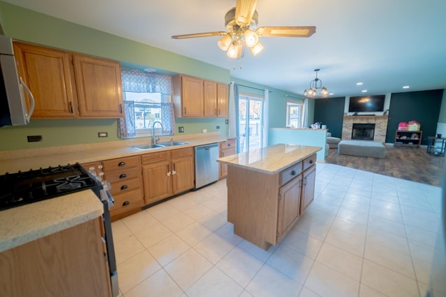 kitchen with sink, dishwasher, a center island, a fireplace, and gas range