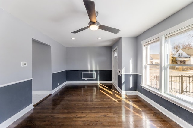 unfurnished room featuring ceiling fan, a healthy amount of sunlight, and dark hardwood / wood-style flooring