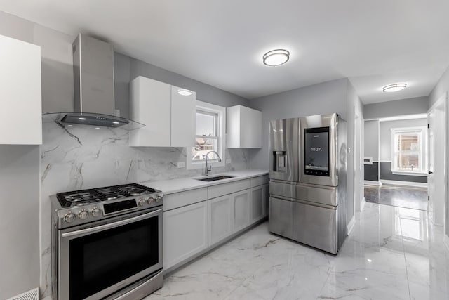 kitchen featuring wall chimney range hood, sink, white cabinetry, stainless steel appliances, and a healthy amount of sunlight