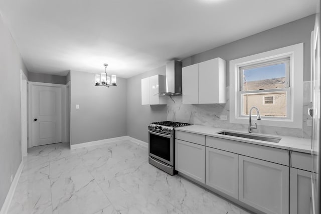 kitchen with sink, stainless steel gas range oven, decorative light fixtures, a chandelier, and wall chimney range hood