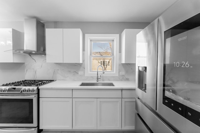 kitchen with stainless steel appliances, sink, white cabinets, and wall chimney exhaust hood