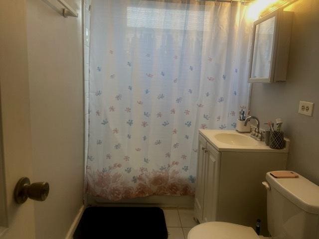 bathroom featuring tile patterned flooring, vanity, a shower with shower curtain, and toilet