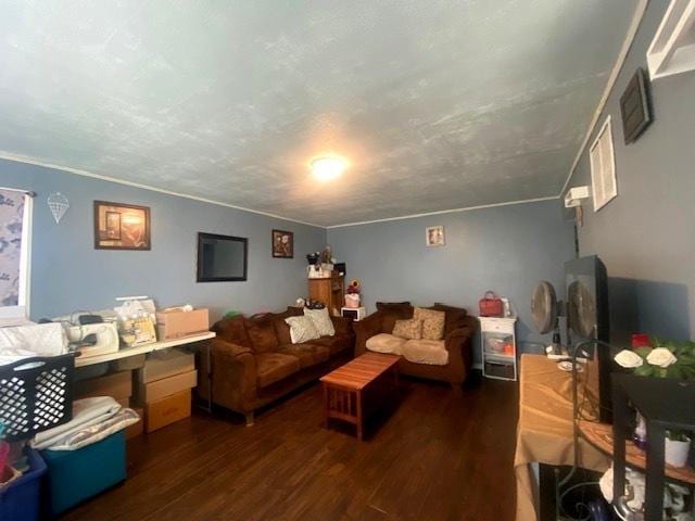 living room featuring dark wood-type flooring, ornamental molding, and a textured ceiling