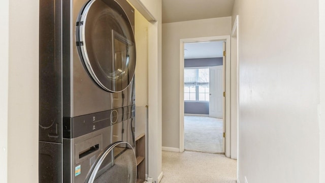 laundry area with laundry area, carpet, stacked washer and clothes dryer, and baseboards