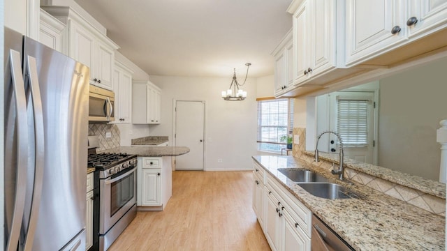 kitchen with appliances with stainless steel finishes, light wood-style flooring, a sink, and white cabinetry