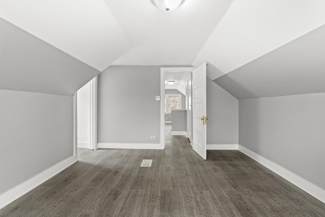 additional living space featuring dark wood-type flooring and vaulted ceiling