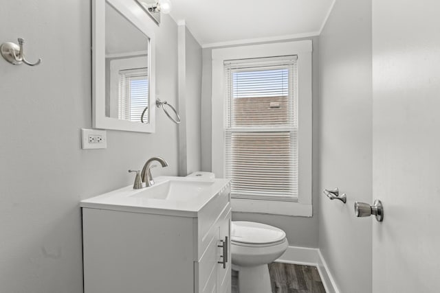 bathroom with hardwood / wood-style flooring, vanity, crown molding, and toilet