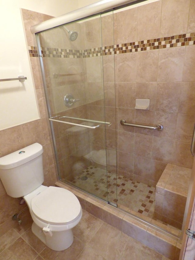 bathroom with tile patterned flooring, walk in shower, tile walls, and toilet