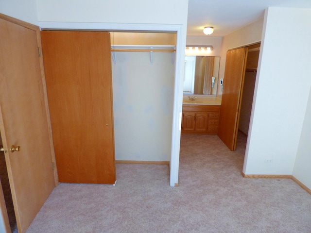 unfurnished bedroom with sink, light carpet, and two closets