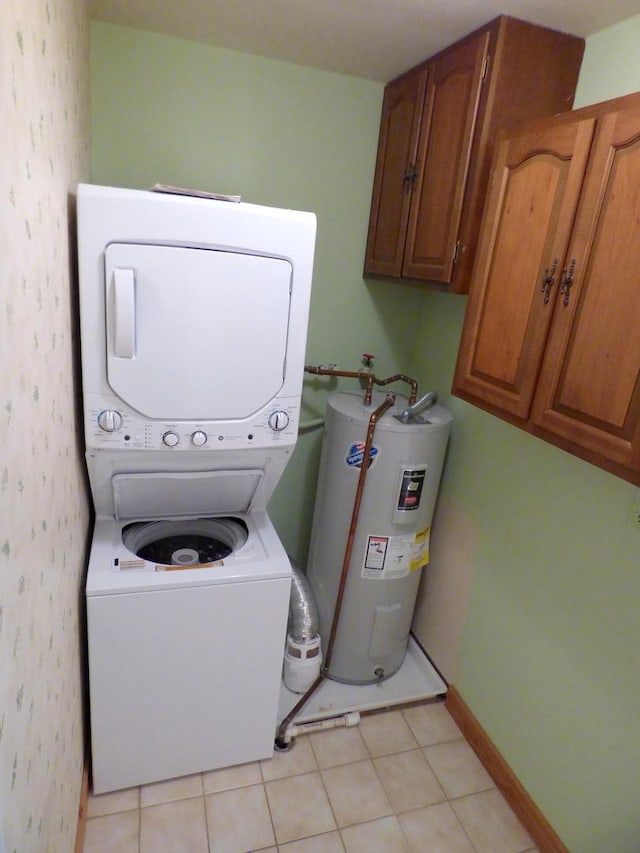 laundry area featuring cabinets, stacked washing maching and dryer, electric water heater, and light tile patterned floors