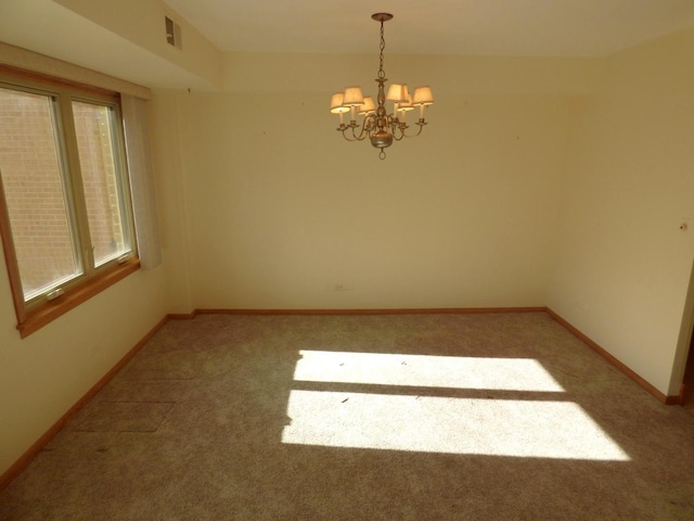 carpeted spare room featuring a chandelier