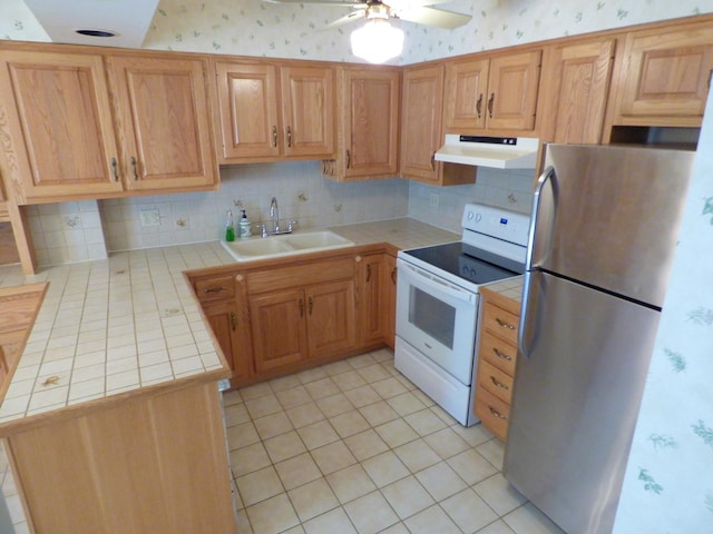 kitchen with tile countertops, white electric range, stainless steel refrigerator, sink, and light tile patterned floors