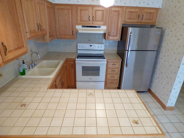 kitchen featuring sink, stainless steel refrigerator, white electric range oven, decorative backsplash, and tile countertops