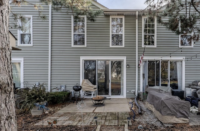 rear view of house featuring a fire pit and a patio