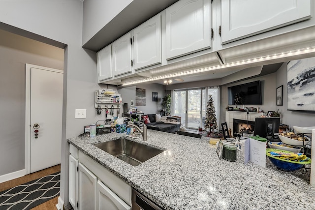 kitchen with white cabinetry, light stone countertops, sink, and light hardwood / wood-style flooring