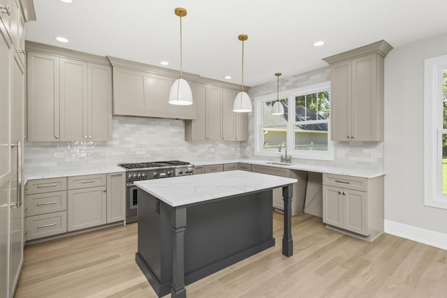 kitchen featuring sink, light hardwood / wood-style flooring, high end range, hanging light fixtures, and a center island