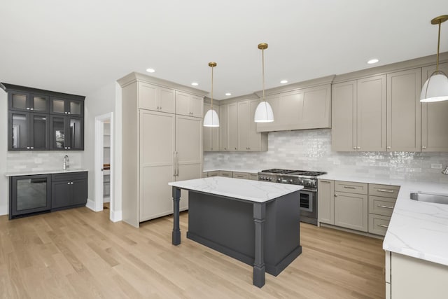 kitchen featuring pendant lighting, light hardwood / wood-style flooring, gray cabinetry, high end stainless steel range, and a kitchen island