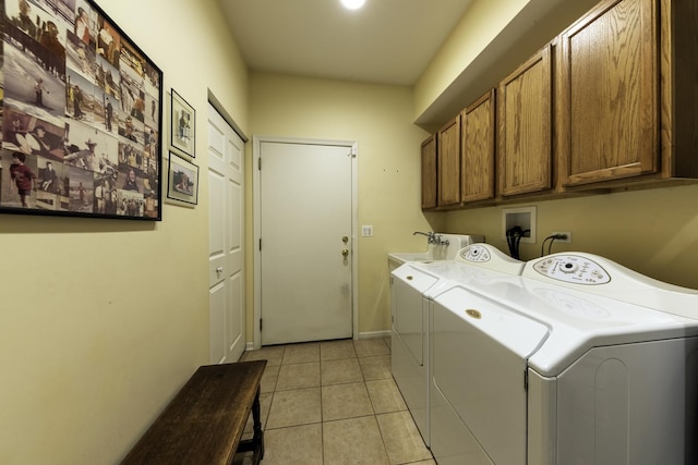 laundry room featuring light tile patterned floors, washer and clothes dryer, and cabinets