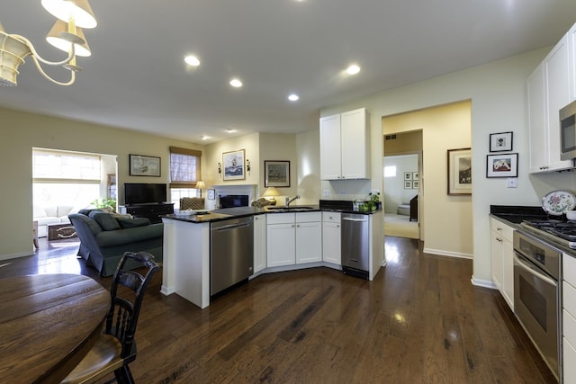 kitchen featuring dark hardwood / wood-style floors, white cabinetry, sink, kitchen peninsula, and stainless steel appliances