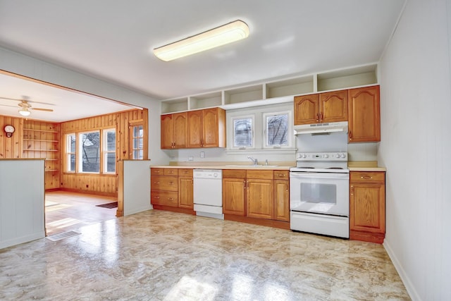 kitchen featuring sink, white appliances, ceiling fan, and wood walls