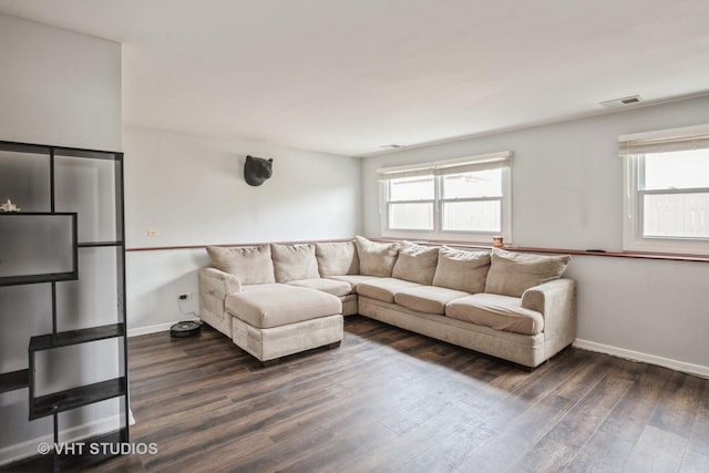 living room featuring dark wood-type flooring and a healthy amount of sunlight