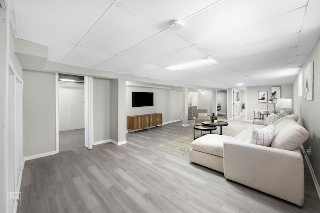 living room with a drop ceiling and light hardwood / wood-style flooring