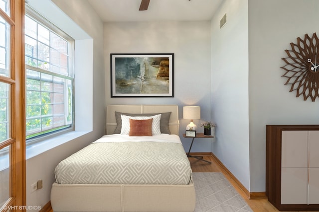 bedroom with multiple windows, ceiling fan, and light wood-type flooring