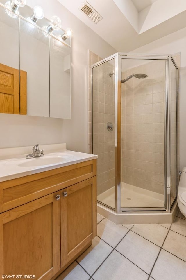 bathroom featuring tile patterned flooring, vanity, a shower with door, and toilet