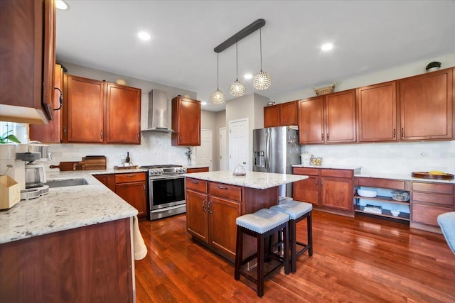 kitchen with stainless steel appliances, a center island, light stone countertops, and wall chimney range hood