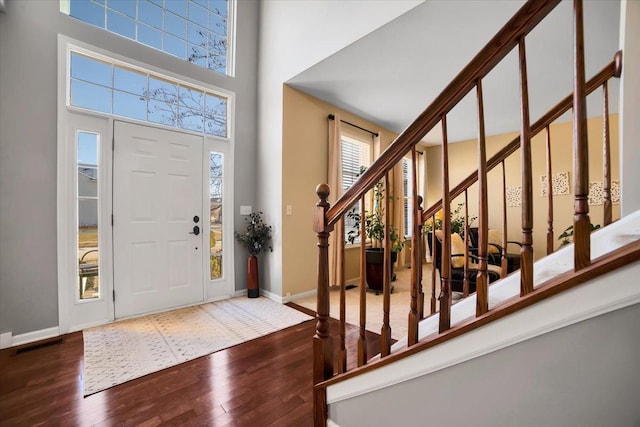 entrance foyer with dark wood-type flooring and a towering ceiling