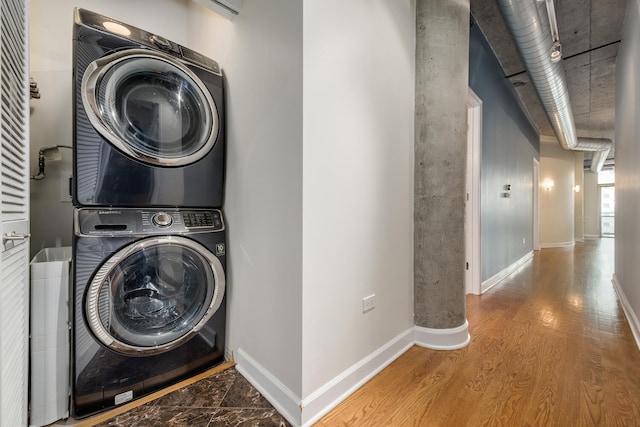 laundry area with wood-type flooring and stacked washer / dryer