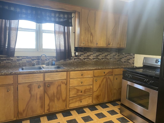 kitchen featuring stainless steel gas range, sink, and decorative backsplash