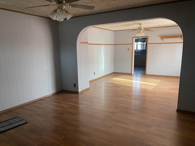 empty room featuring wood-type flooring, ceiling fan, and wood walls