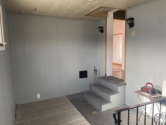 staircase with carpet floors and wooden walls