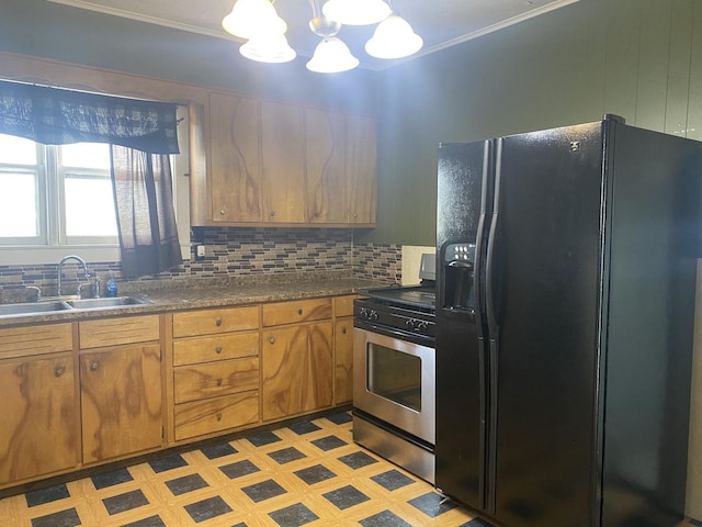 kitchen with stainless steel range with gas cooktop, sink, backsplash, black fridge, and an inviting chandelier