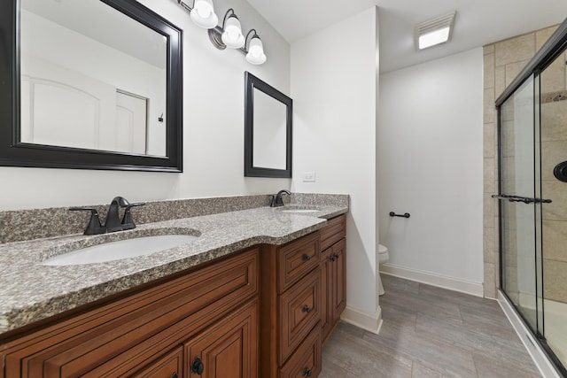 bathroom featuring vanity, a shower with shower door, and toilet