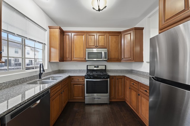 kitchen featuring dark hardwood / wood-style flooring, sink, stainless steel appliances, and light stone countertops