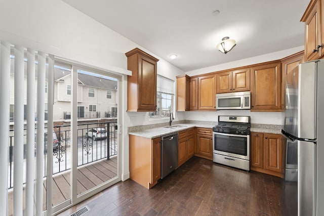 kitchen featuring stainless steel appliances, sink, dark wood-type flooring, and light stone counters