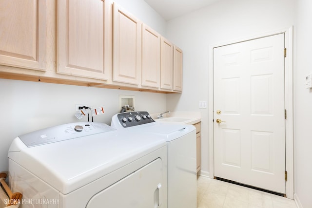 clothes washing area featuring cabinets, sink, and washing machine and dryer