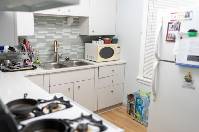 kitchen featuring tasteful backsplash, white appliances, white cabinetry, and sink