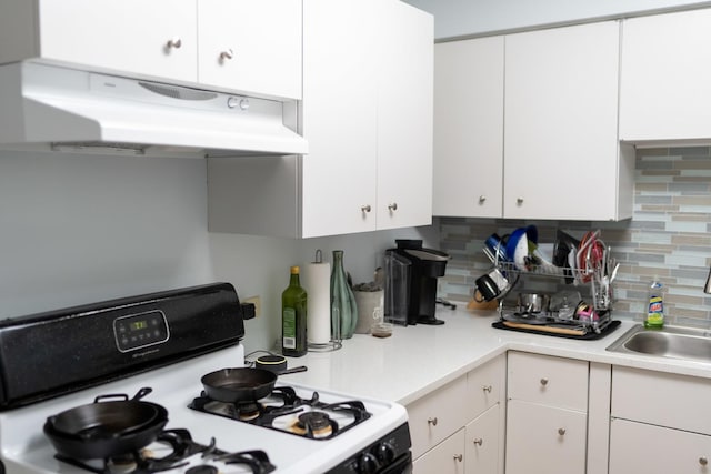 kitchen featuring tasteful backsplash, sink, white range with gas stovetop, and white cabinets