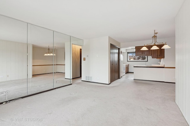 unfurnished living room with light colored carpet and sink