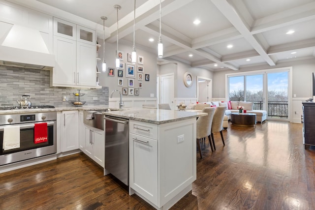 kitchen featuring white cabinetry, stainless steel appliances, custom exhaust hood, and beamed ceiling