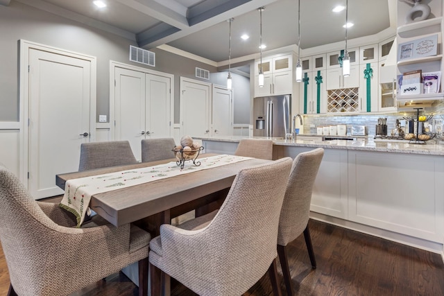 dining area with coffered ceiling, ornamental molding, dark hardwood / wood-style floors, wet bar, and beam ceiling