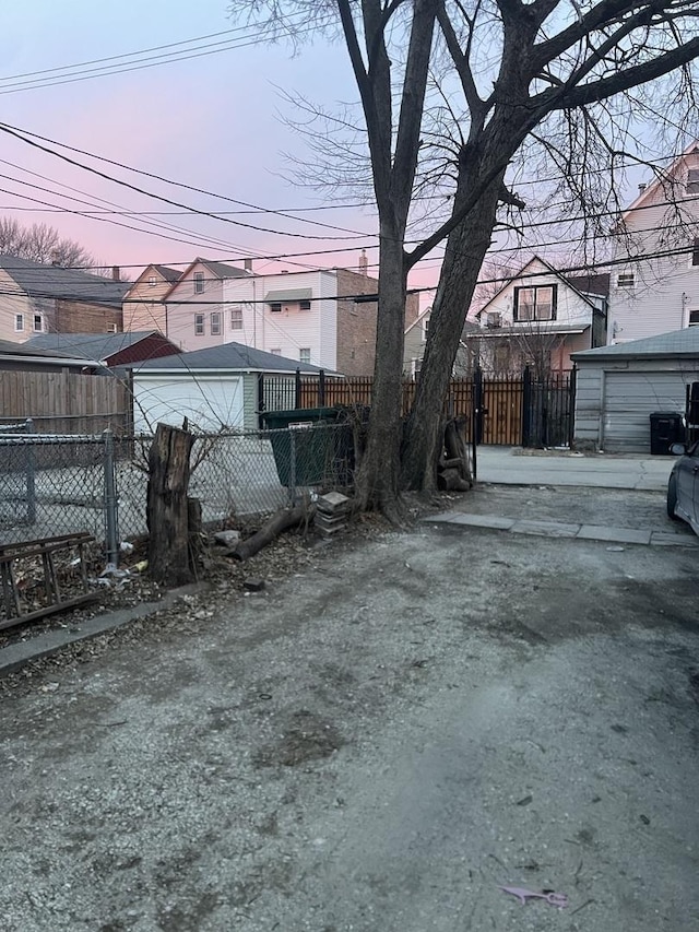 yard at dusk featuring a garage and an outbuilding