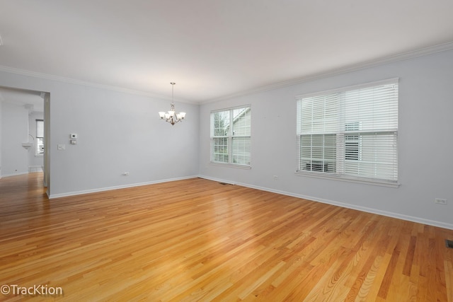 empty room featuring a notable chandelier, ornamental molding, and light wood-type flooring