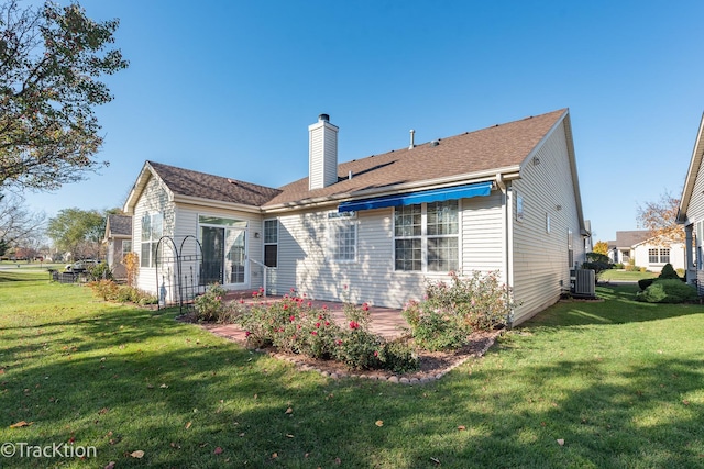 rear view of house with a yard and central AC