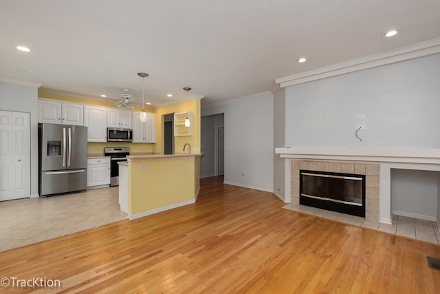 kitchen with hanging light fixtures, crown molding, appliances with stainless steel finishes, and white cabinets